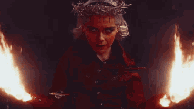 a woman with a crown on her head is holding a sword and fire