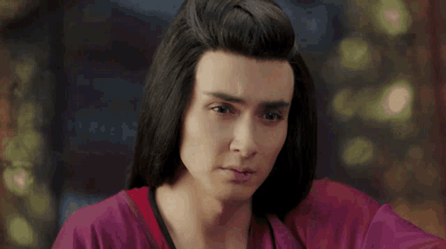 a man with long hair is wearing a purple robe