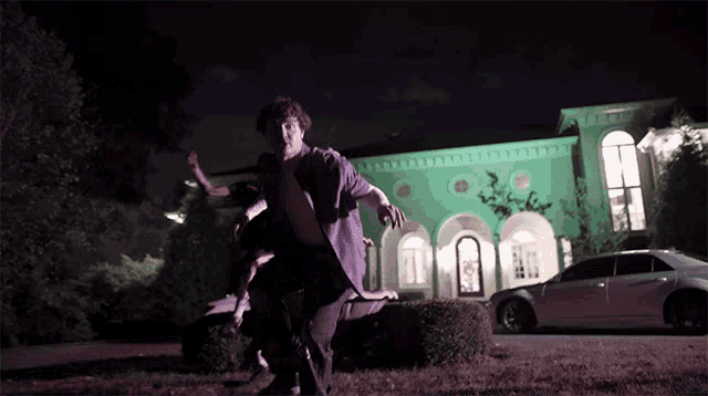 a man in a suit is running in front of a green building