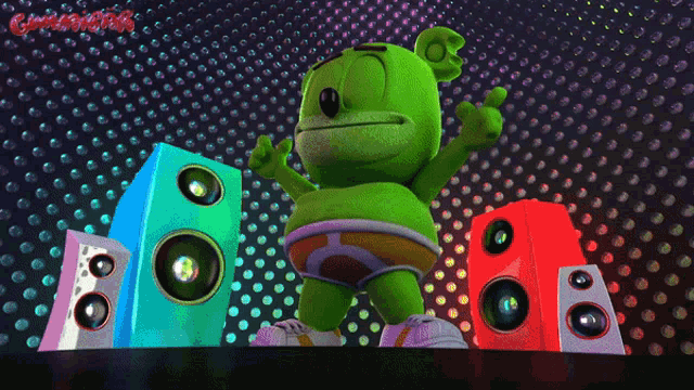 a green gummy bear is standing in front of speakers with the word gummy bear written on the bottom