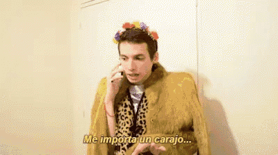 a man in a fur coat is talking on a cell phone while wearing a flower crown .
