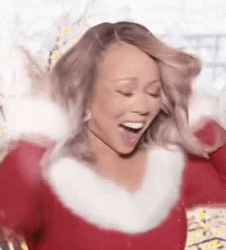 mariah carey is wearing a santa claus costume and smiling with her mouth open .