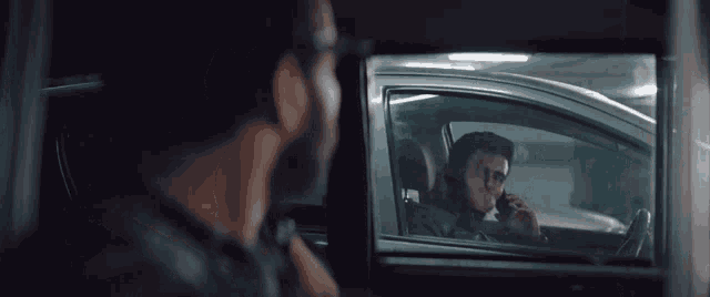 a man is talking on a cell phone while driving a car