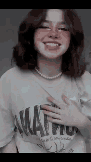 a girl wearing a pearl necklace and a t-shirt that says " wait "