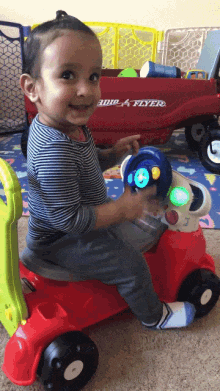 a little boy is playing with a red radio flyer toy