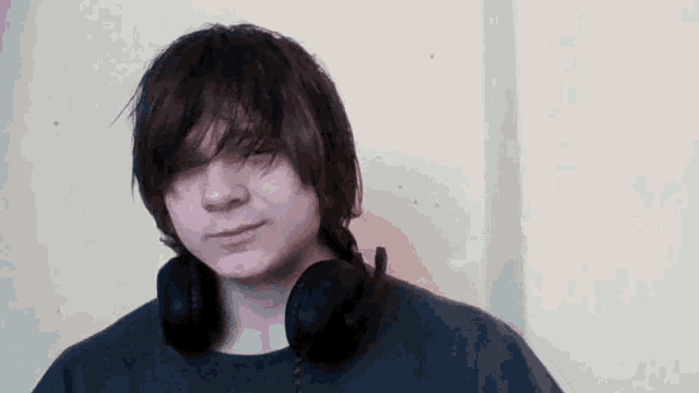 a young man wearing headphones and a black shirt looks at the camera