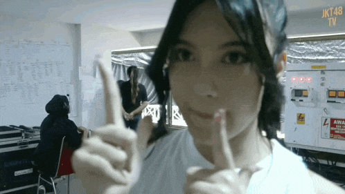 a woman making a peace sign in front of a jkt48 sign