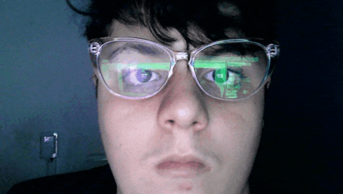 a close up of a person 's face with glasses and a reflection of a computer screen