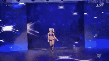 a woman in a bikini is walking down a stage in front of a blue background .