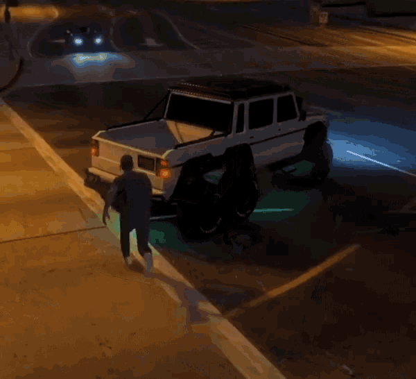 a man is standing next to a white truck that is parked on the side of the road at night