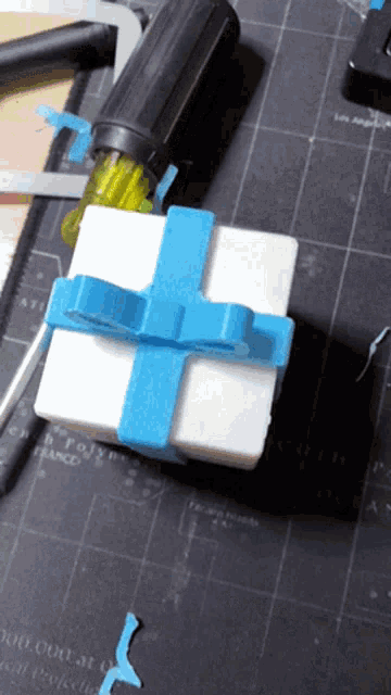 a white box with a blue bow is on a cutting mat