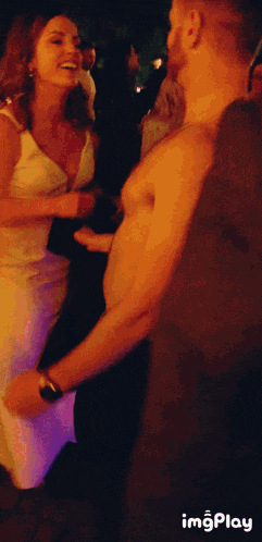 a man without a shirt is dancing with a woman at a party