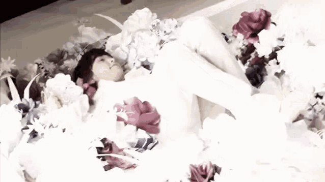 a person is laying on a bed surrounded by flowers .