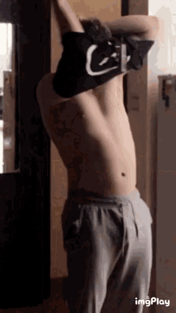 a shirtless man is taking off his shirt in a room .