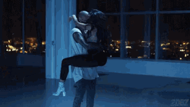 a man is holding a woman in his arms in a room with a sign that says starz
