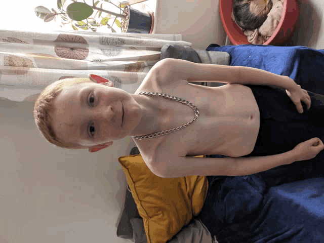 a shirtless boy with a chain around his neck