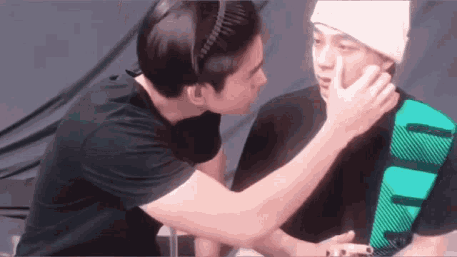 a man kissing another man on the cheek while wearing a white hat