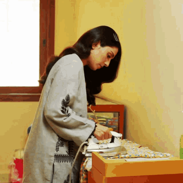 a woman is ironing a piece of cloth on a dresser