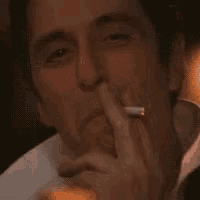 a man is smiling while holding a cigarette in his hand .