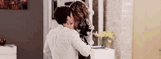 a man and a woman kissing in a living room .
