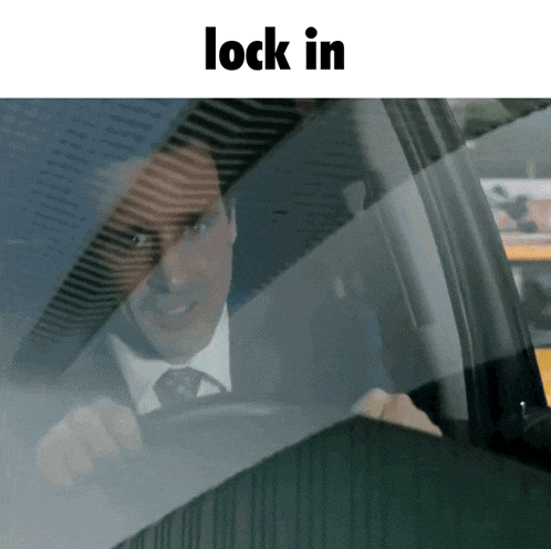 a man in a suit and tie is driving a car and the words lock in are below him