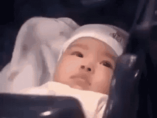 a baby wearing a white hat is laying in a crib .