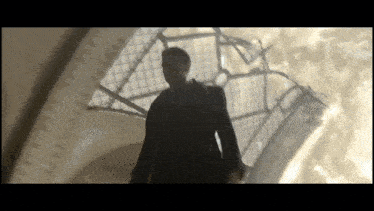 a man in a suit and tie stands in front of a broken window