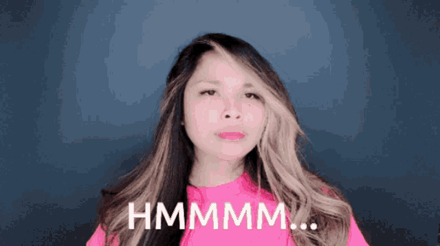 a woman in a pink shirt has the word hmmmm written on her face