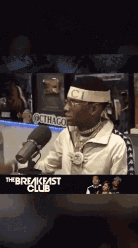 a man wearing a headband that says ' ci ' on it stands in front of a microphone