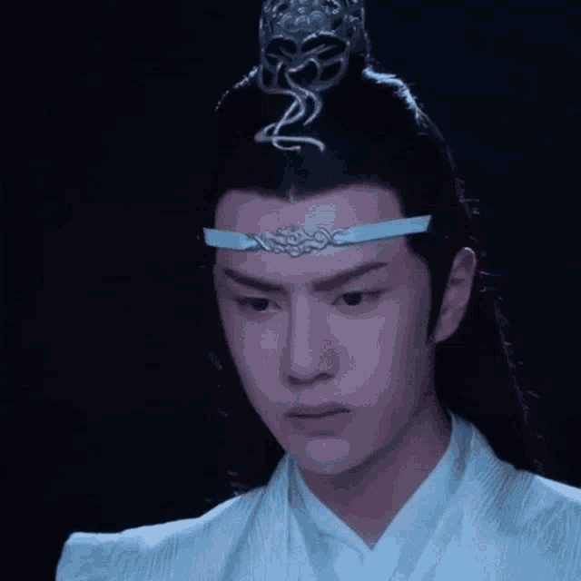 a close up of a man wearing a blue headband and a crown .