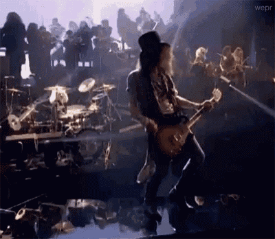 a man in a hat is playing a guitar on a stage .