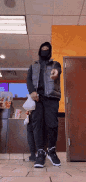 a man wearing a black mask is standing in a store