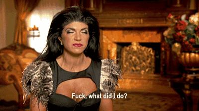 a woman in a black dress says " fuck what did i do " in front of a fireplace