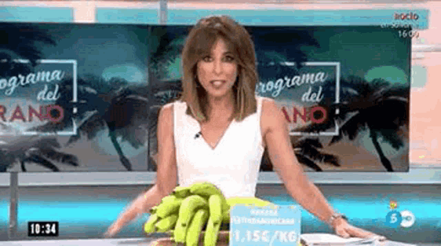 a woman is holding a bunch of bananas in front of a screen that says programa del ano