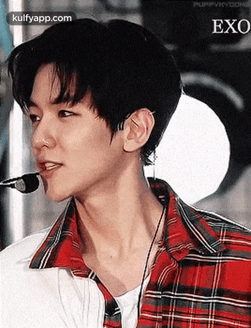 a close up of a person wearing a plaid shirt and earbuds .
