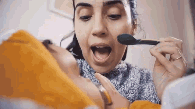 a woman feeding a baby with a spoon in her mouth