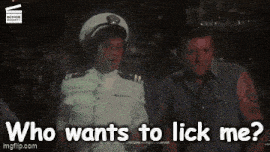 a man in a captain 's hat is talking to another man in a bar and asking who wants to lick me