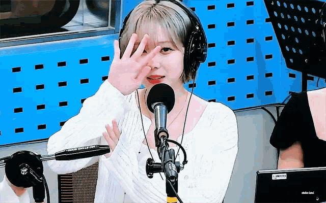 a woman wearing headphones stands in front of a microphone in a studio