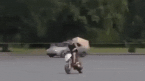 a man riding a motorcycle in front of a white car