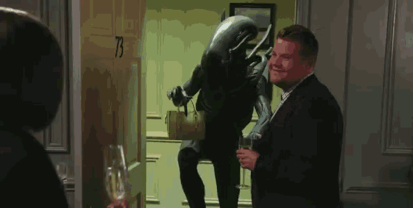 a man in a suit is standing next to a statue of an alien