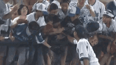 a baseball player is being attacked by a crowd of people while standing in the stands .