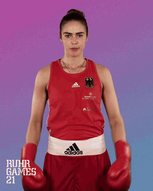 a woman wearing boxing gloves and a red adidas tank top