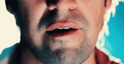a close up of a man 's face with a beard and a mouth open .