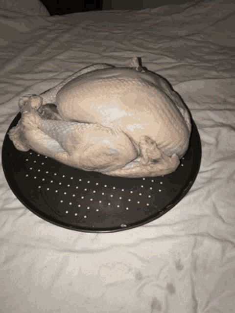 a turkey is sitting on a black plate on top of a bed