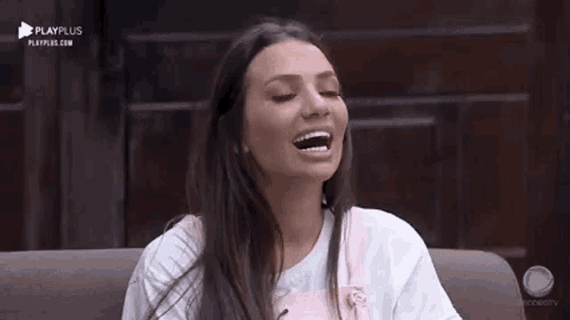 a woman is sitting on a couch laughing and smiling .