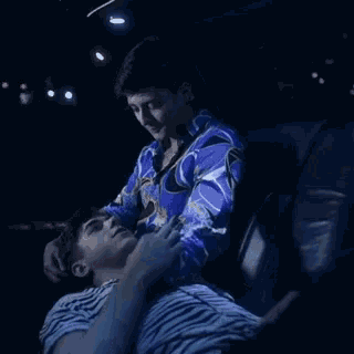 a man in a blue shirt is putting his hand on another man 's neck