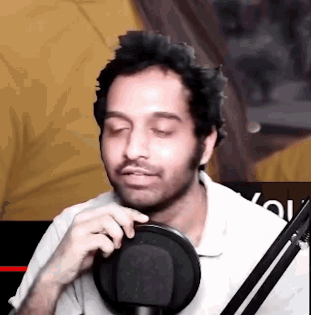 a man with his eyes closed is sitting in front of a microphone .