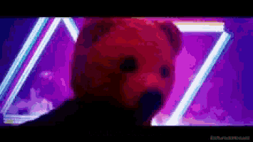 a red teddy bear is standing in front of a purple background with neon lights .