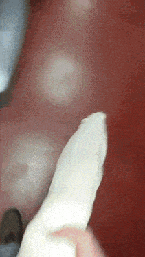 a close up of a person holding a white object with a red background