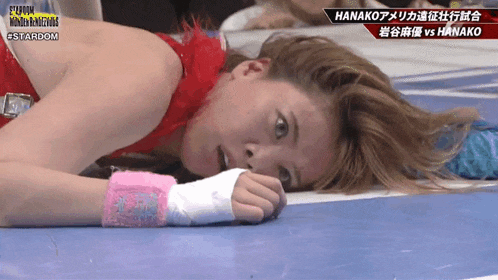 a female wrestler is laying on the floor with the words hanako on the bottom right